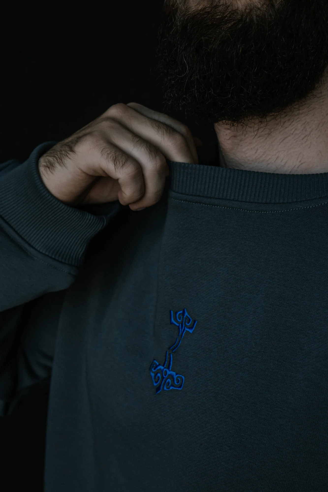 Close-up of the blue Mjolnir embroidery, cotton fabric and ribbed neckline